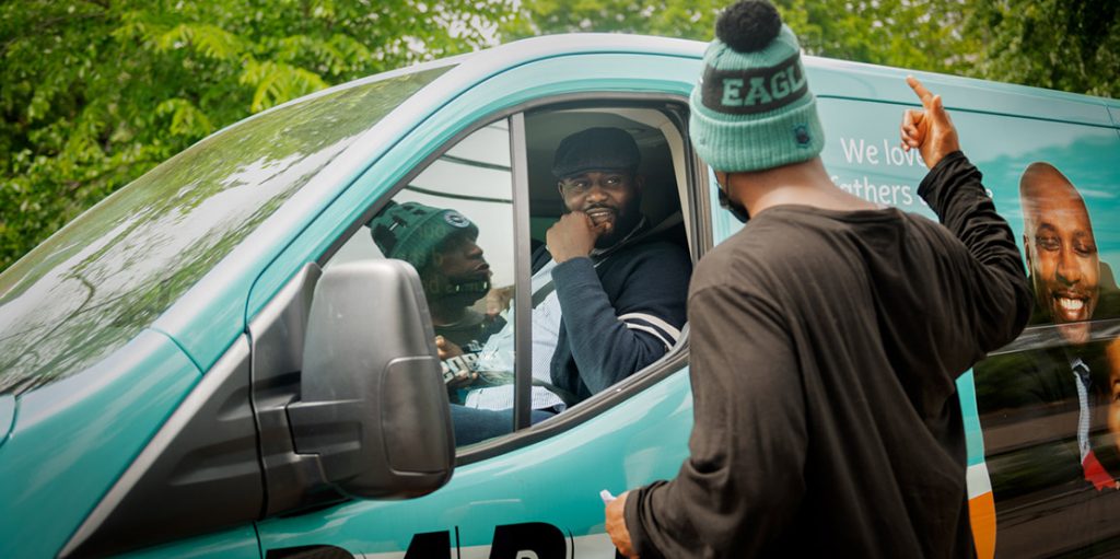 man driving van pulled over talking with man outside of van through open car window