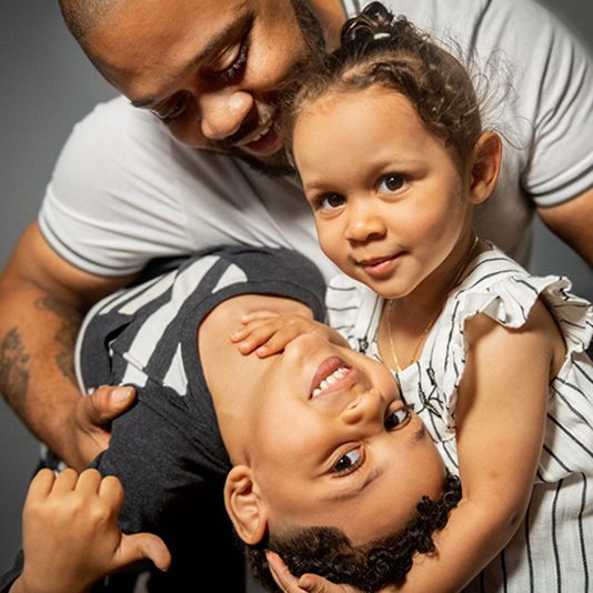 two young kids with their father holding them