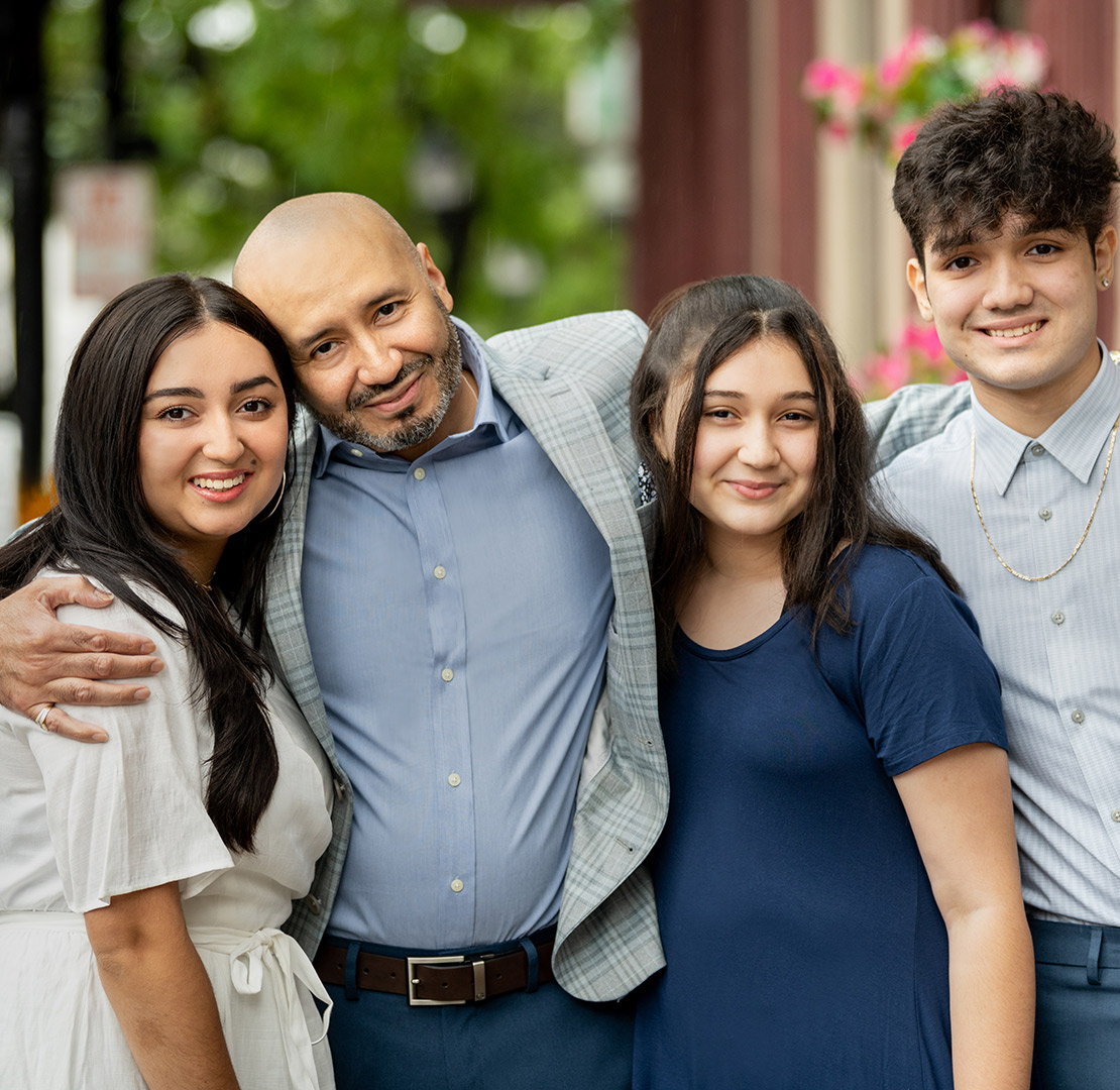 father with his arms around his three teenage children