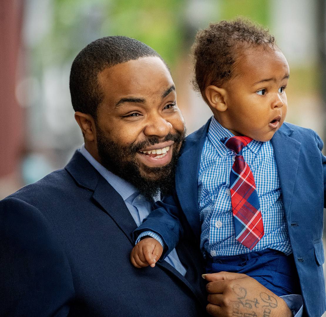 father in a suit holding young son