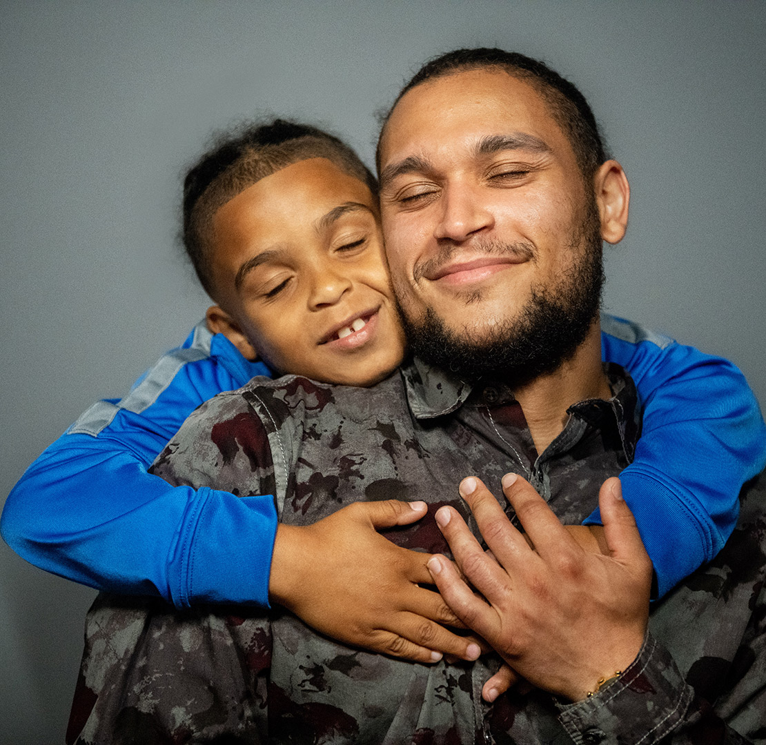 son hugging father from behind